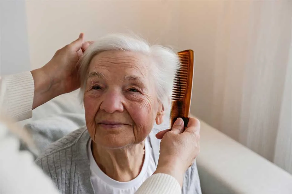 Einer älteren Person werden liebevoll die Haare gekämmt